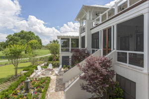 Rear porches of house overlooking raised lawn and fire pit area.