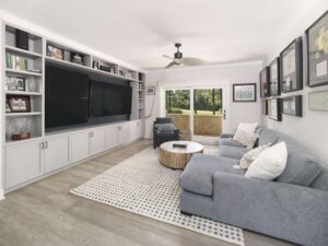 Entertainment area with large built-ins showcasing multiple televisions and view to golf course beyond.