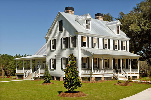 Front view of rehabilitated original circa 1840s farmhouse with front porch and dormers in metal roof.